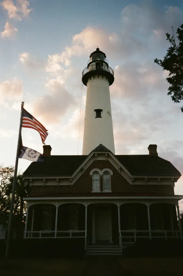 St. Simons Island lighthouse at dusk with an American flag