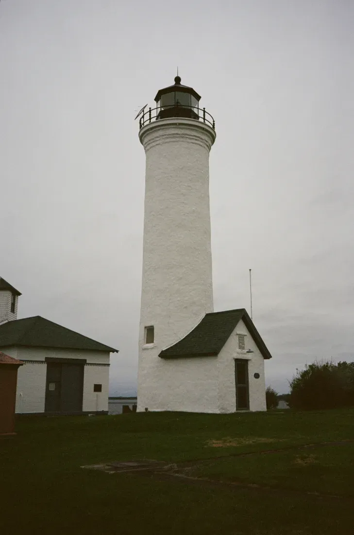 Tibbetts Point lighthouse with small attached buildings on a cloudy day