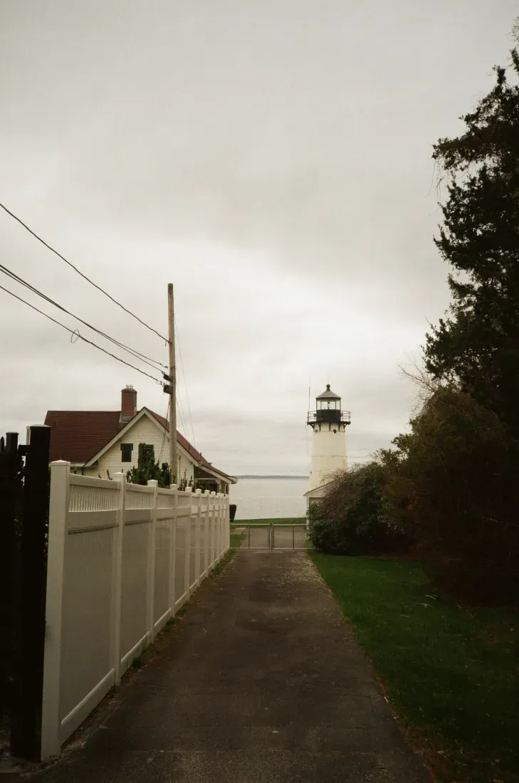 Path leading to the Warwick lighthouse beside houses and trees on an overcast day