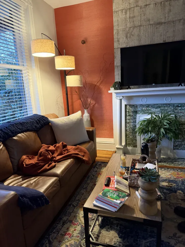 Cozy living room with brown couch, floor lamp, fireplace, coffee table, and large TV