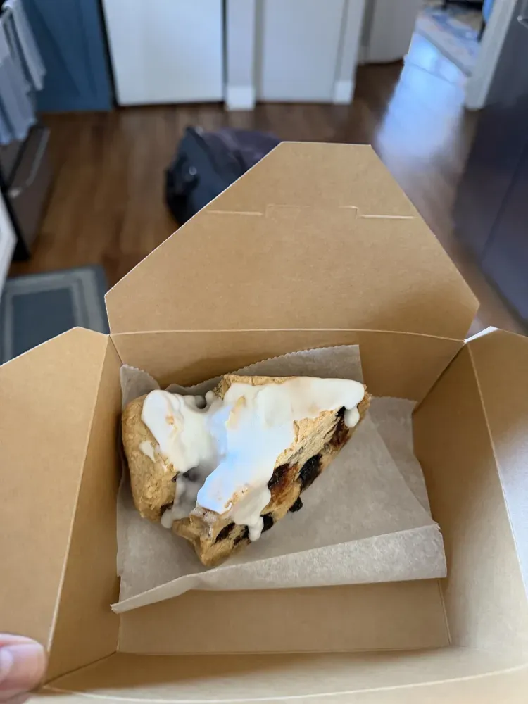 Open cardboard box holding an icing covered scone