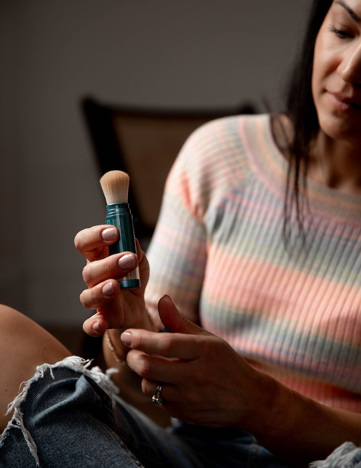 A woman is sitting on a couch holding a brush in her hand.