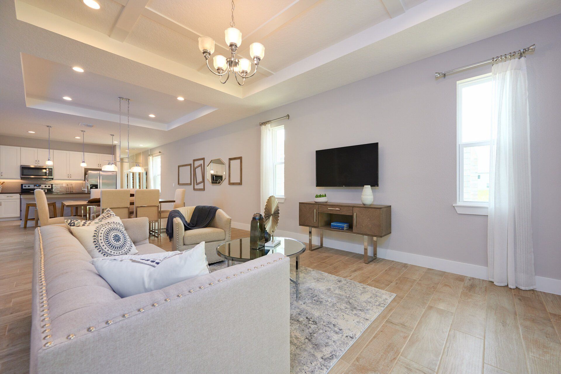 Dining room with neutral décor, large windows, and contemporary chandelier