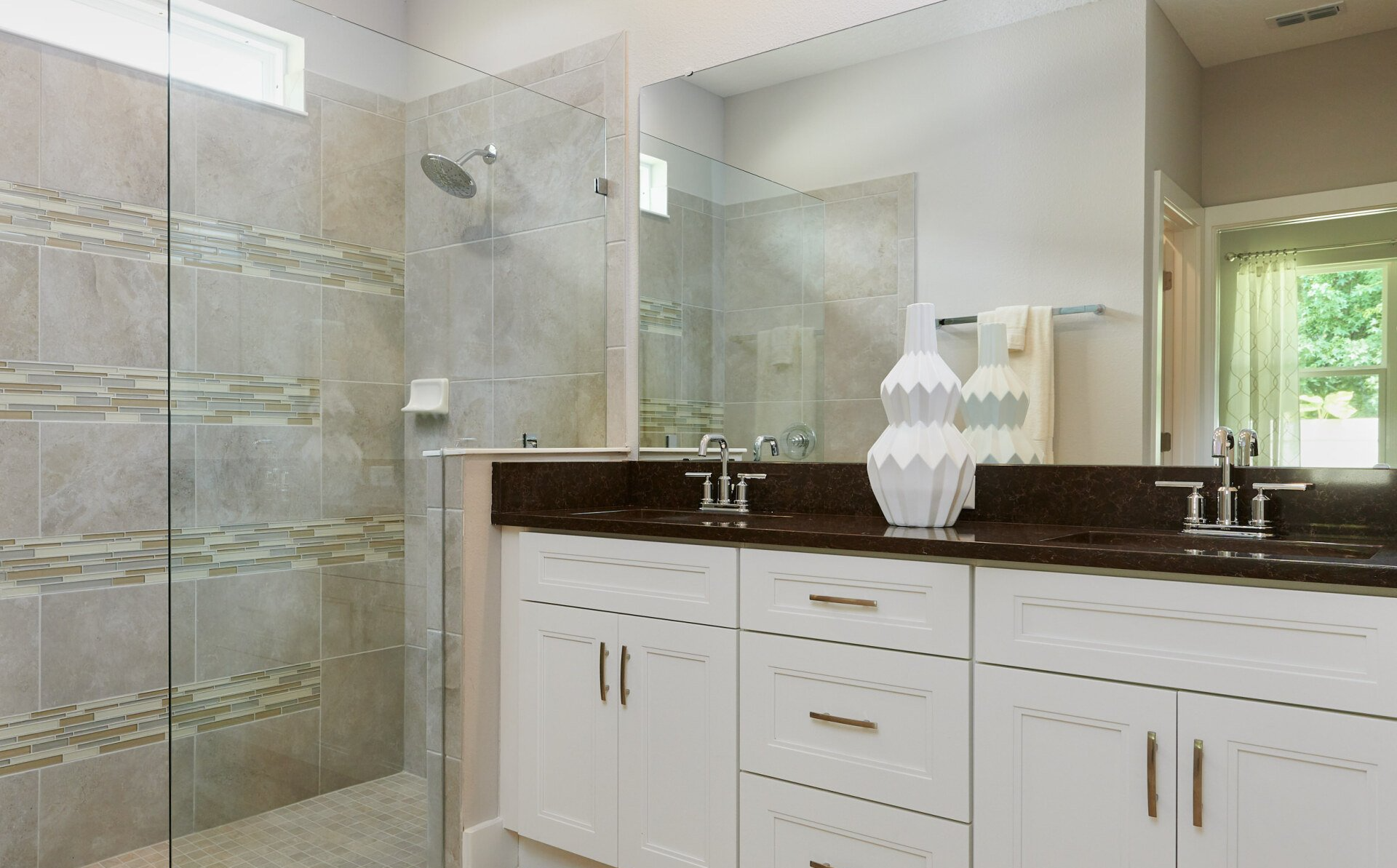 Arisha Enclave bathroom featuring a glass walk-in shower, double vanity, and tile walls.