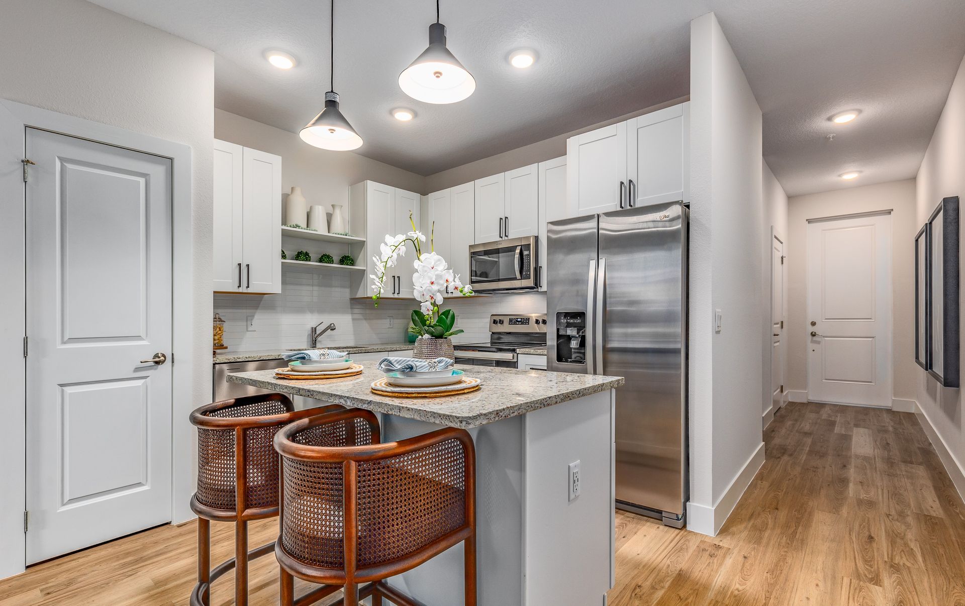 Townhome interior with hallway view leading to white kitchen and wood flooring.