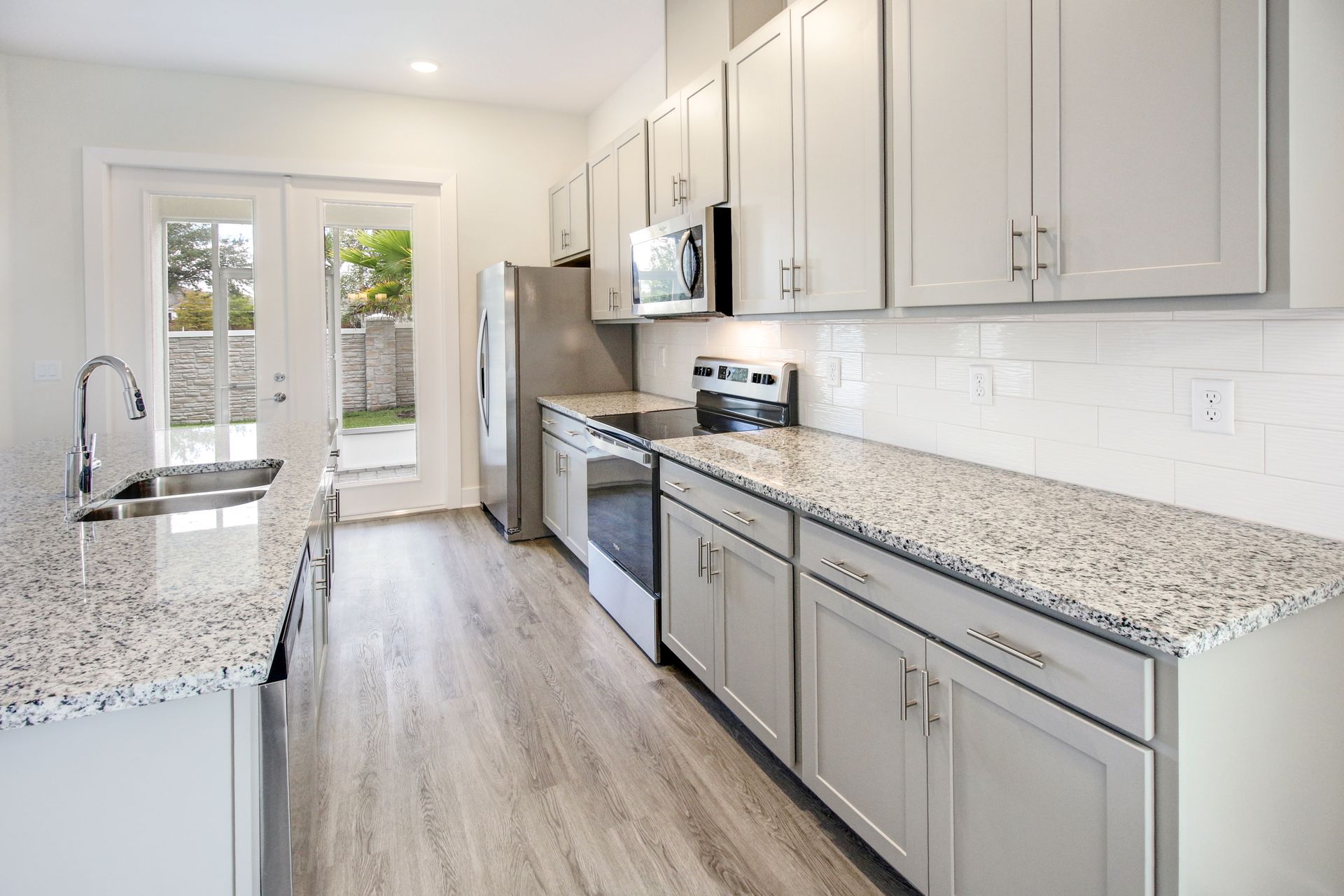 Brentwood Landing hallway view leading into a bright modern kitchen with wood flooring.