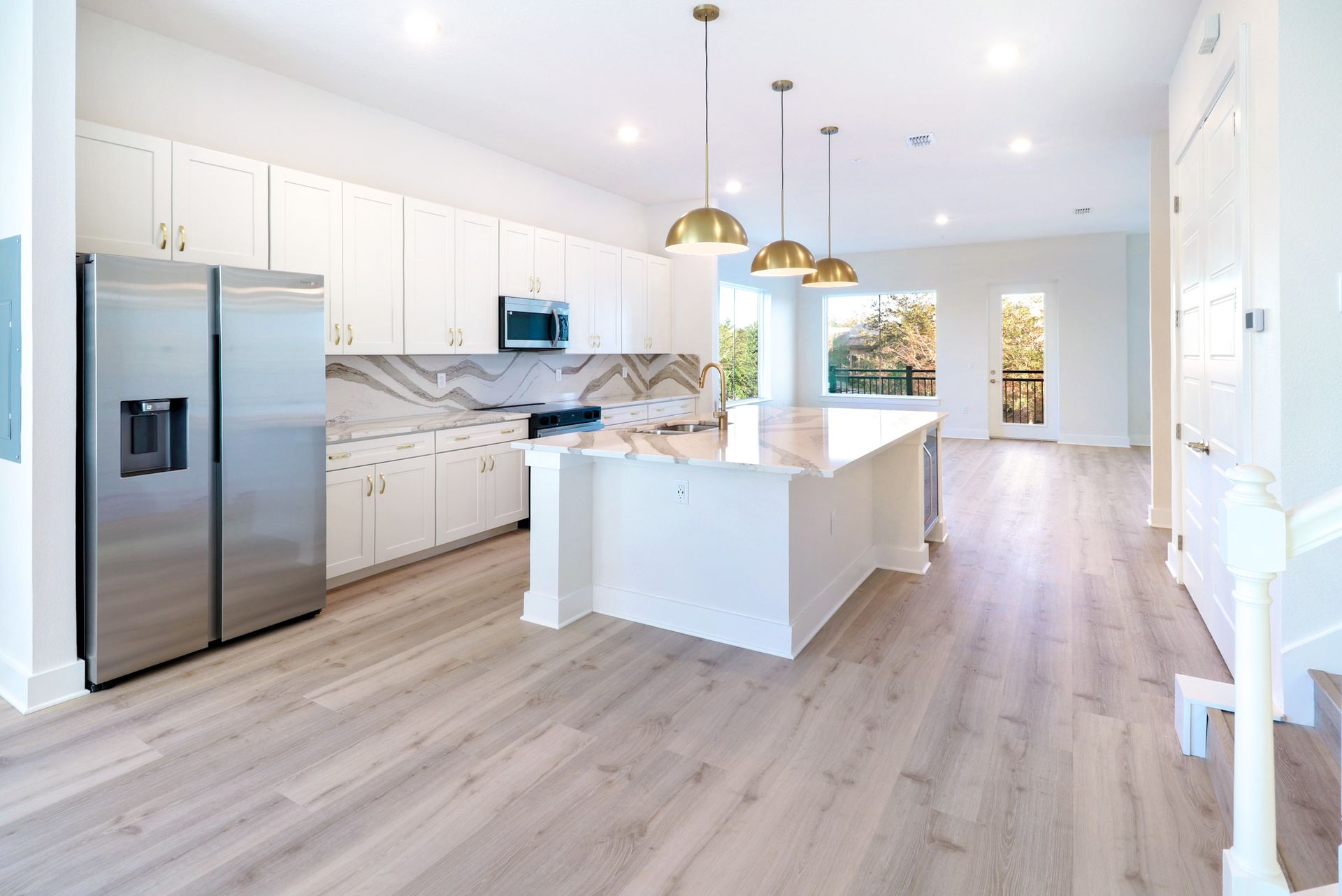 Modern kitchen with white cabinets, quartz countertops, and open living area.