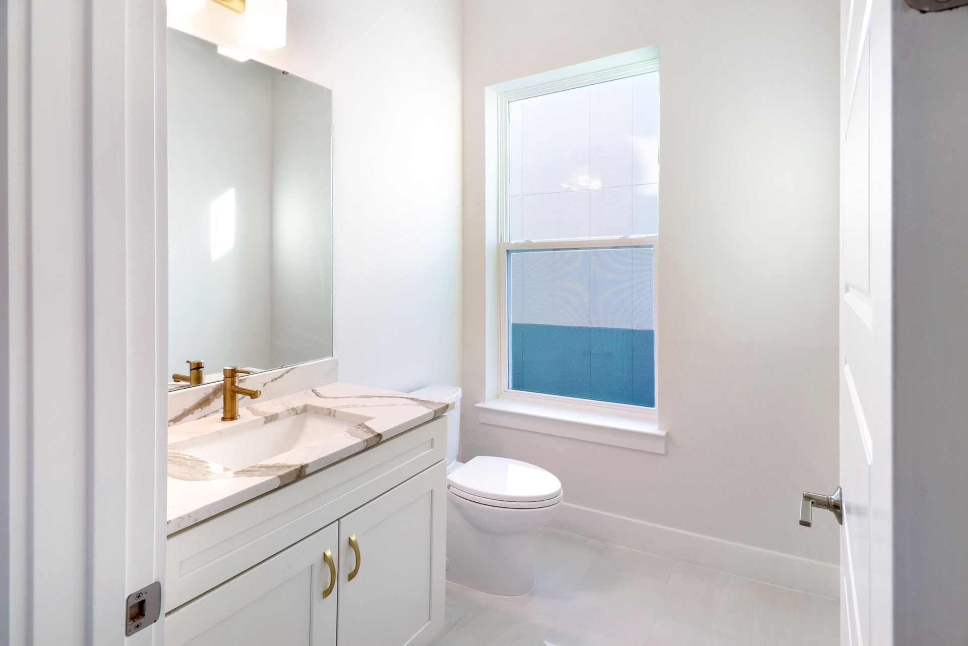 Bathroom with floor-to-ceiling tile, walk-in shower, and natural window lighting.