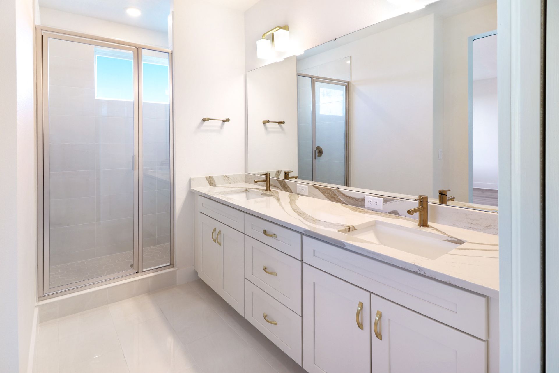 Luxury bathroom featuring double vanity, framed mirrors, and marble-style surfaces.