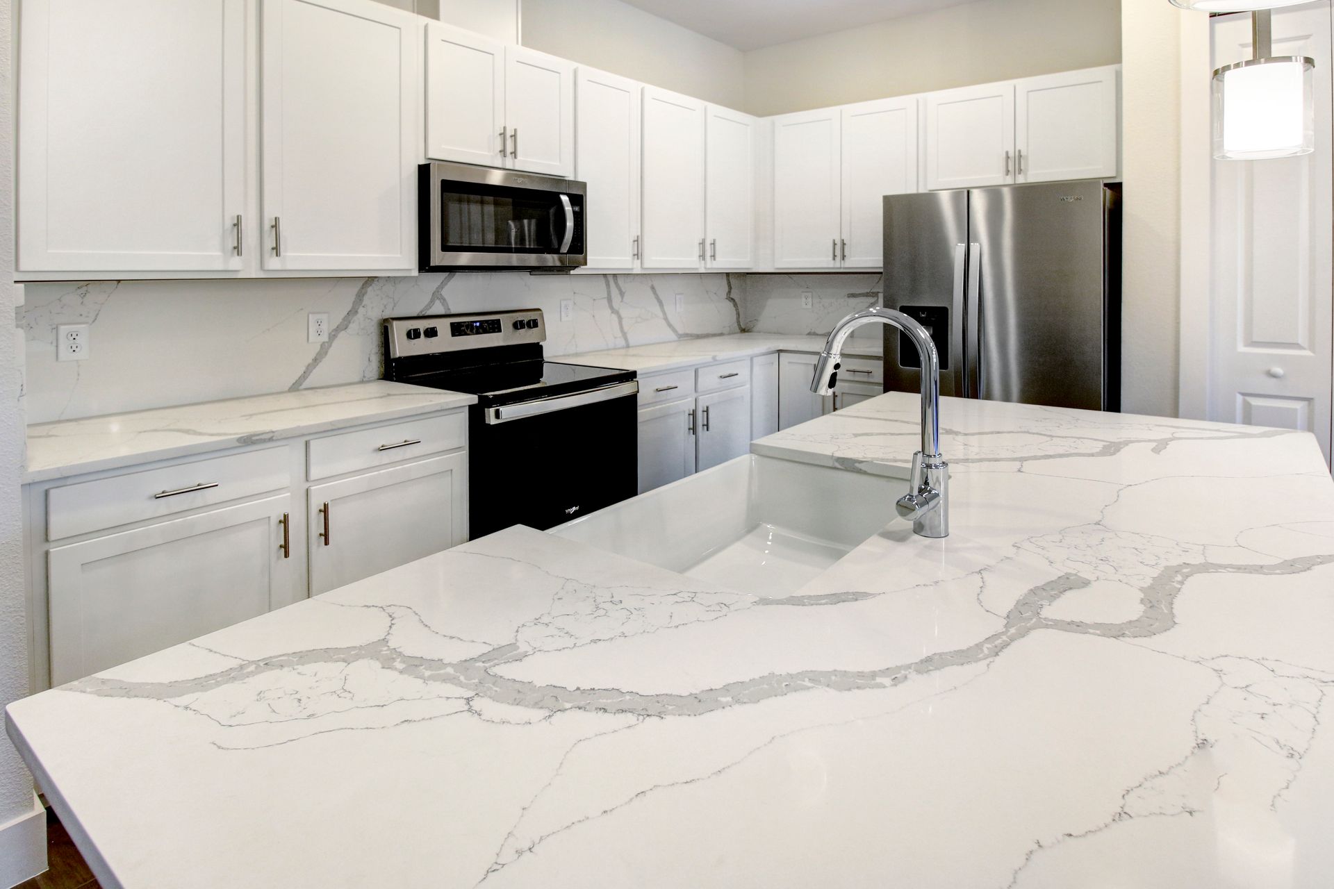 Brentwood Landing modern kitchen featuring white cabinets, quartz countertops, and stainless appliances