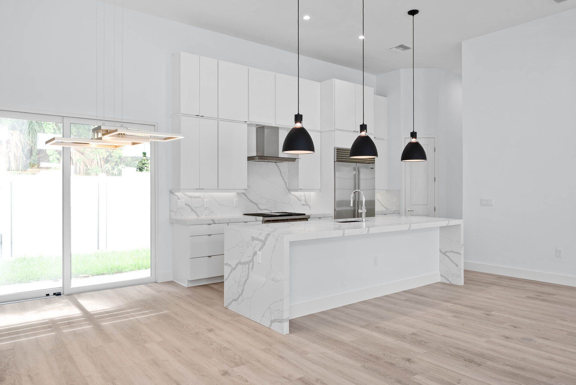 Vilasa Townhomes kitchen with white cabinets, quartz countertops, and black pendant lights