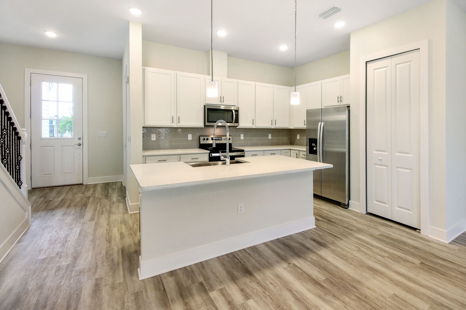 Brentwood Landing open kitchen and living area with white cabinetry and recessed lighting.