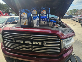 Open truck hood with oil bottles displayed on a maroon RAM pickup | HWY 42 Auto Service
