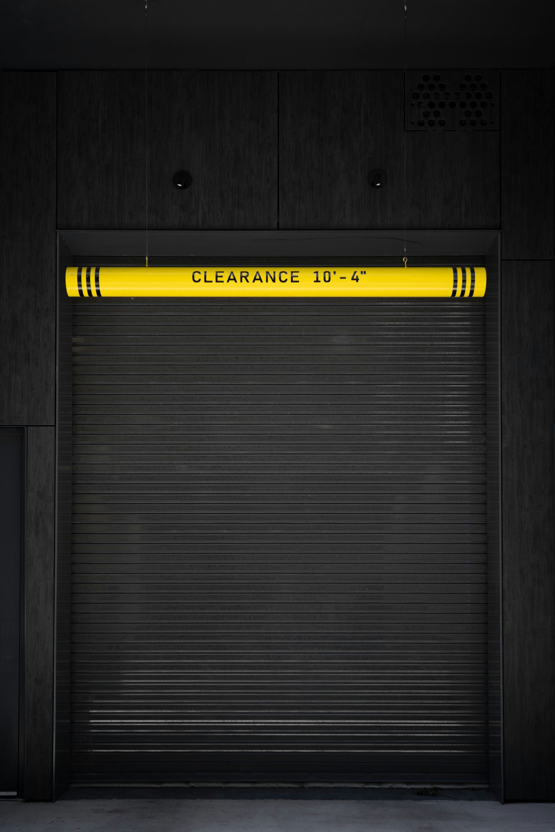 A black garage door with a yellow sign that says clearance 18-4