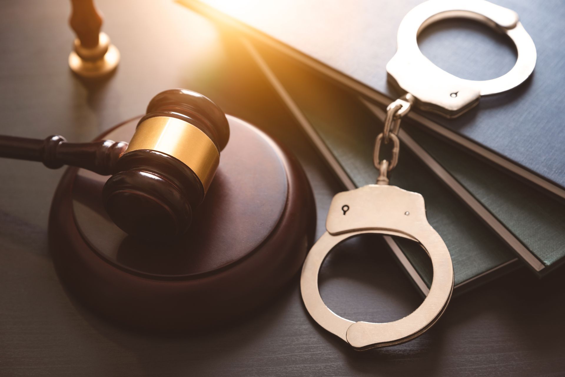 Judge’s gavel beside handcuffs and law books on a desk.