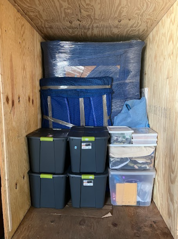 Storage bin with packed items and plastic containers inside a wooden enclosure