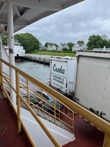 View from a ferry deck toward a dock, waterfront buildings, and cloudy sky