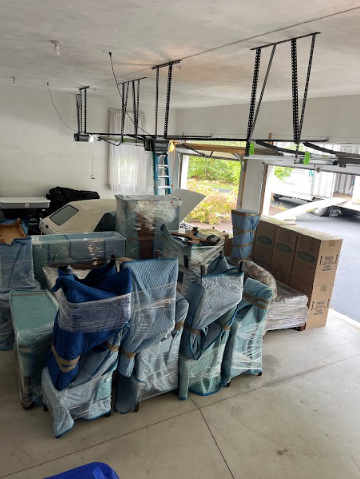 Garage filled with wrapped furniture, boxes, and household items during moving or renovation