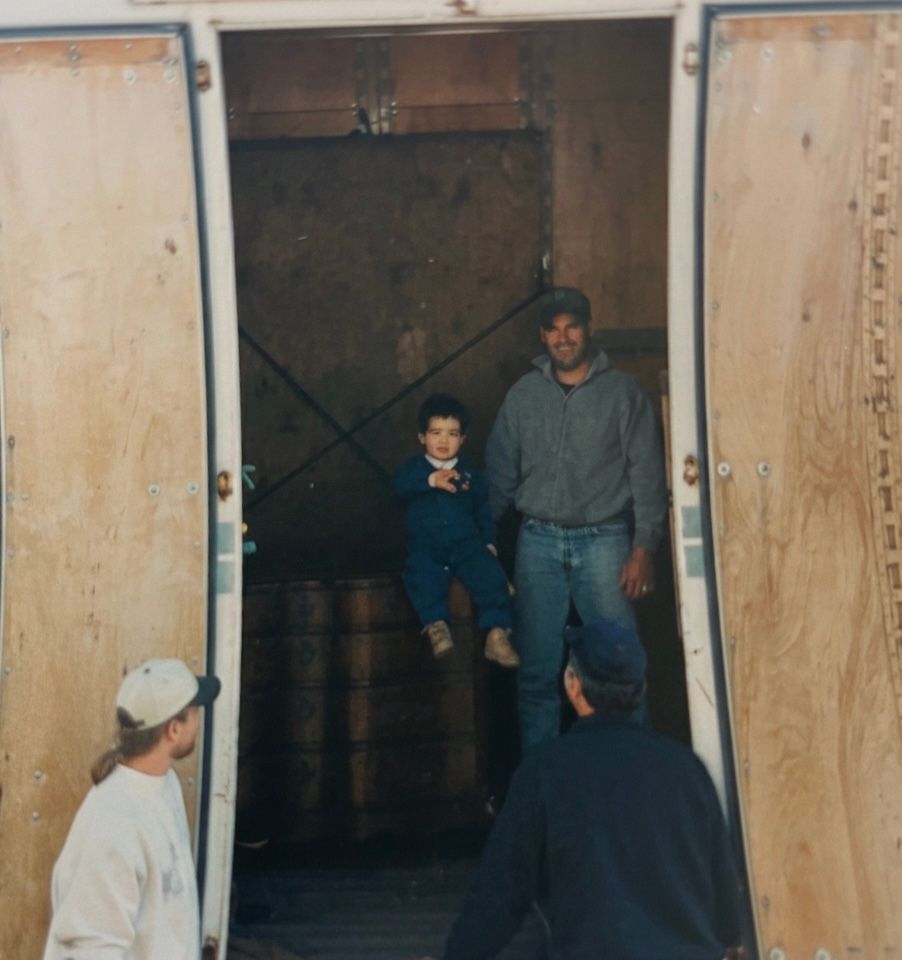 Two people stand in a doorway of a large wooden crate while others look on.