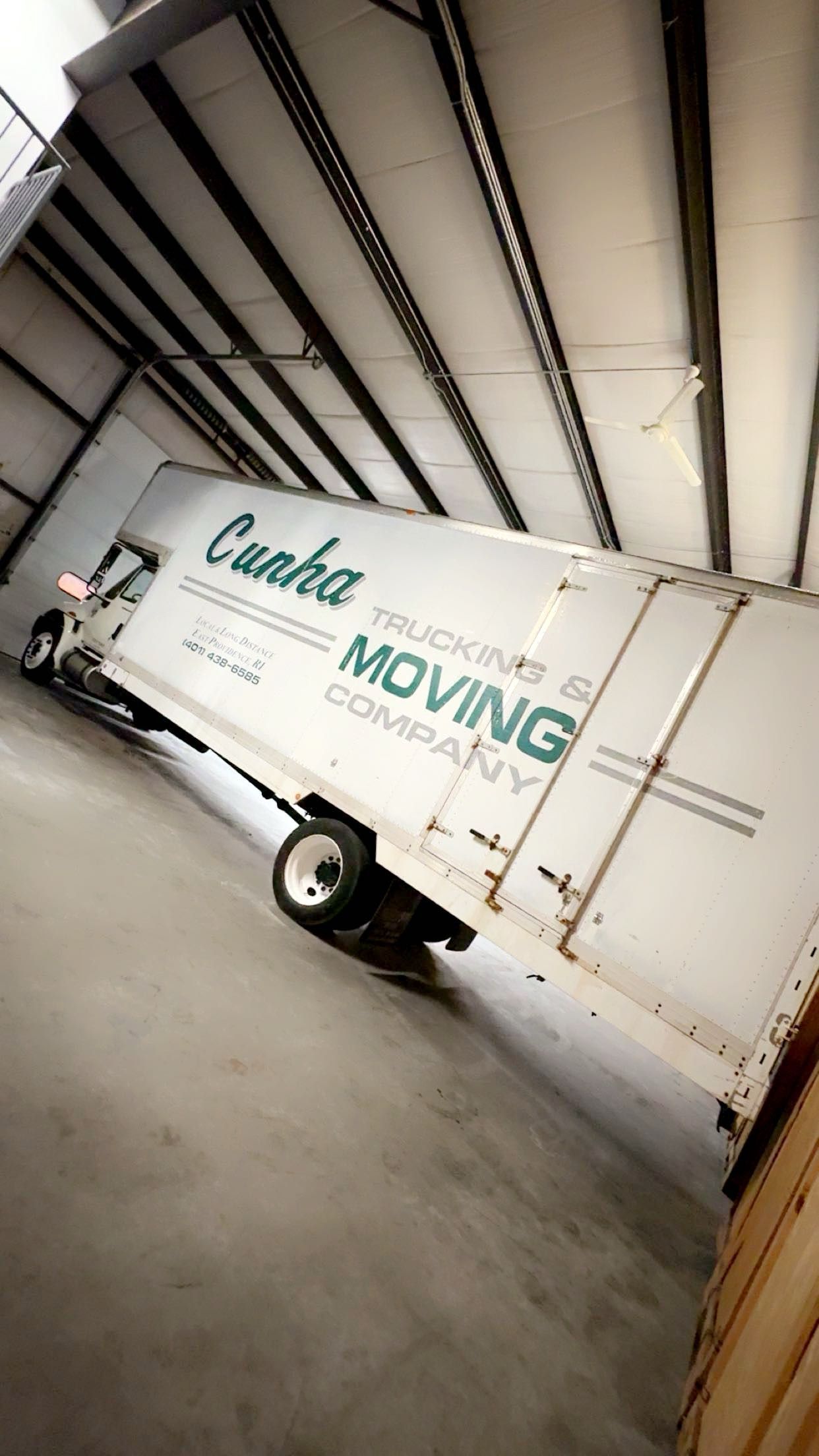 White moving truck parked inside a warehouse with large green 