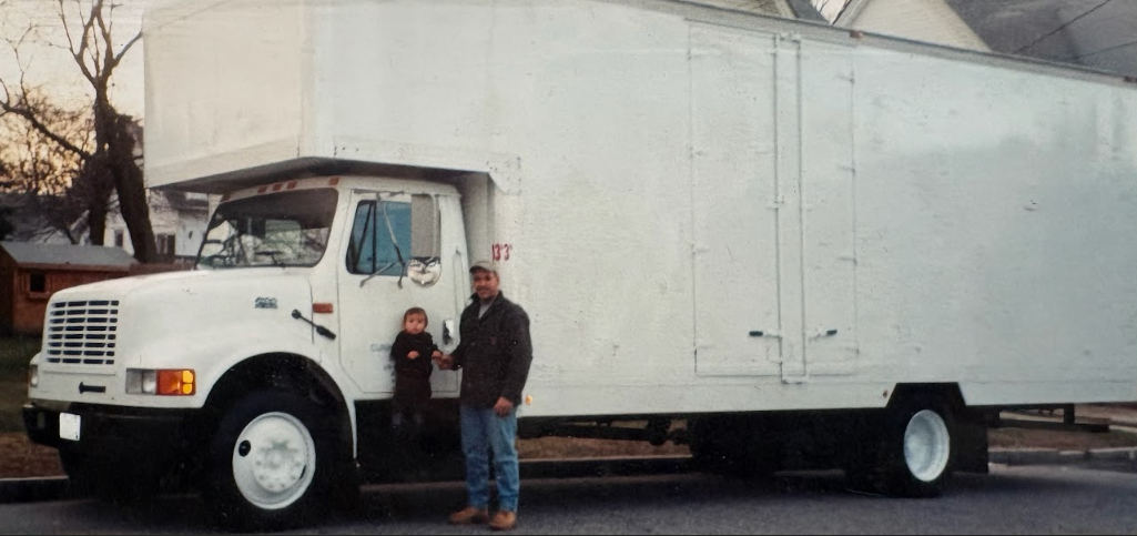 White box truck parked with a man standing beside the cab.