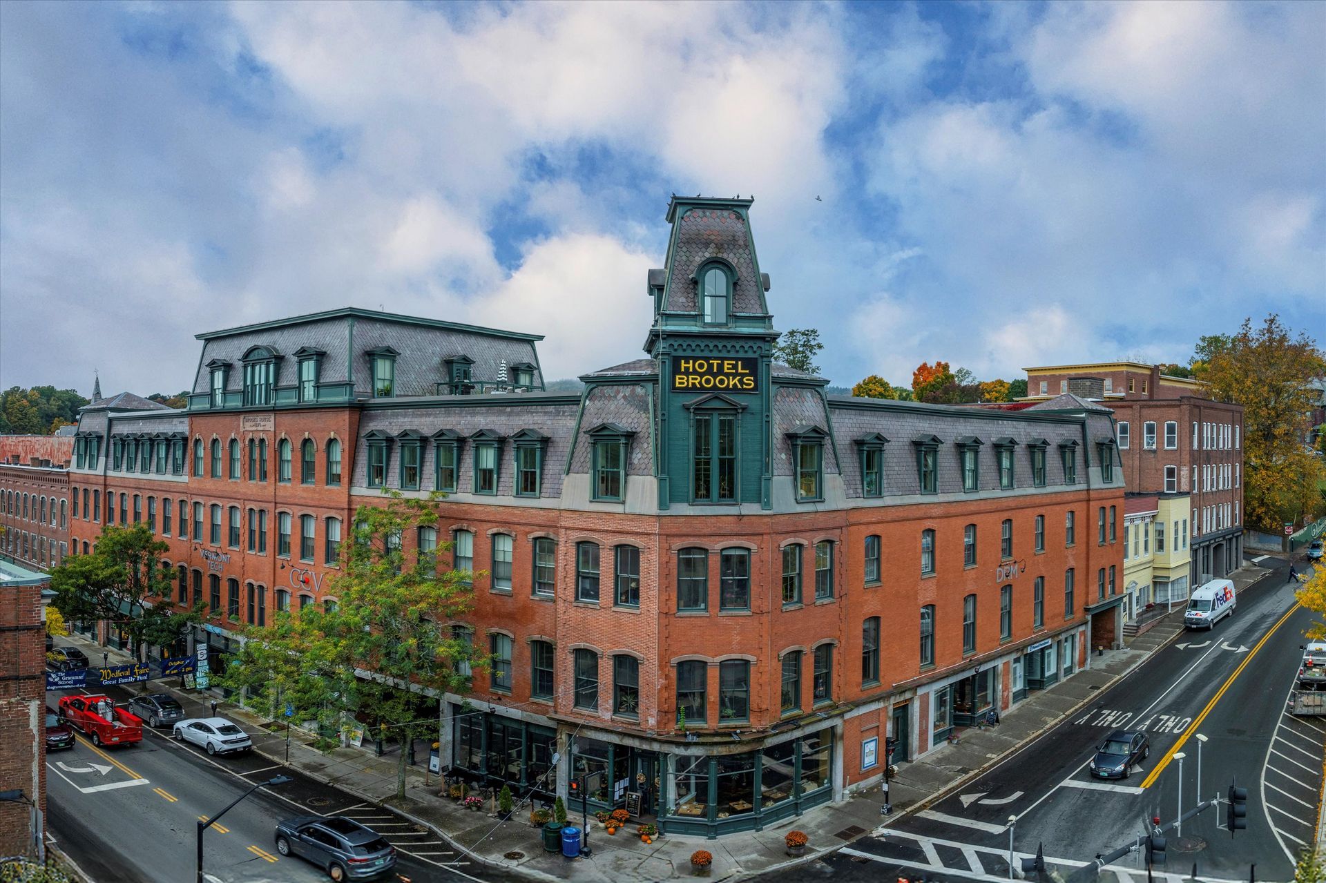 Corner brick building with a tower on a rainy street corner under a cloudy sky.