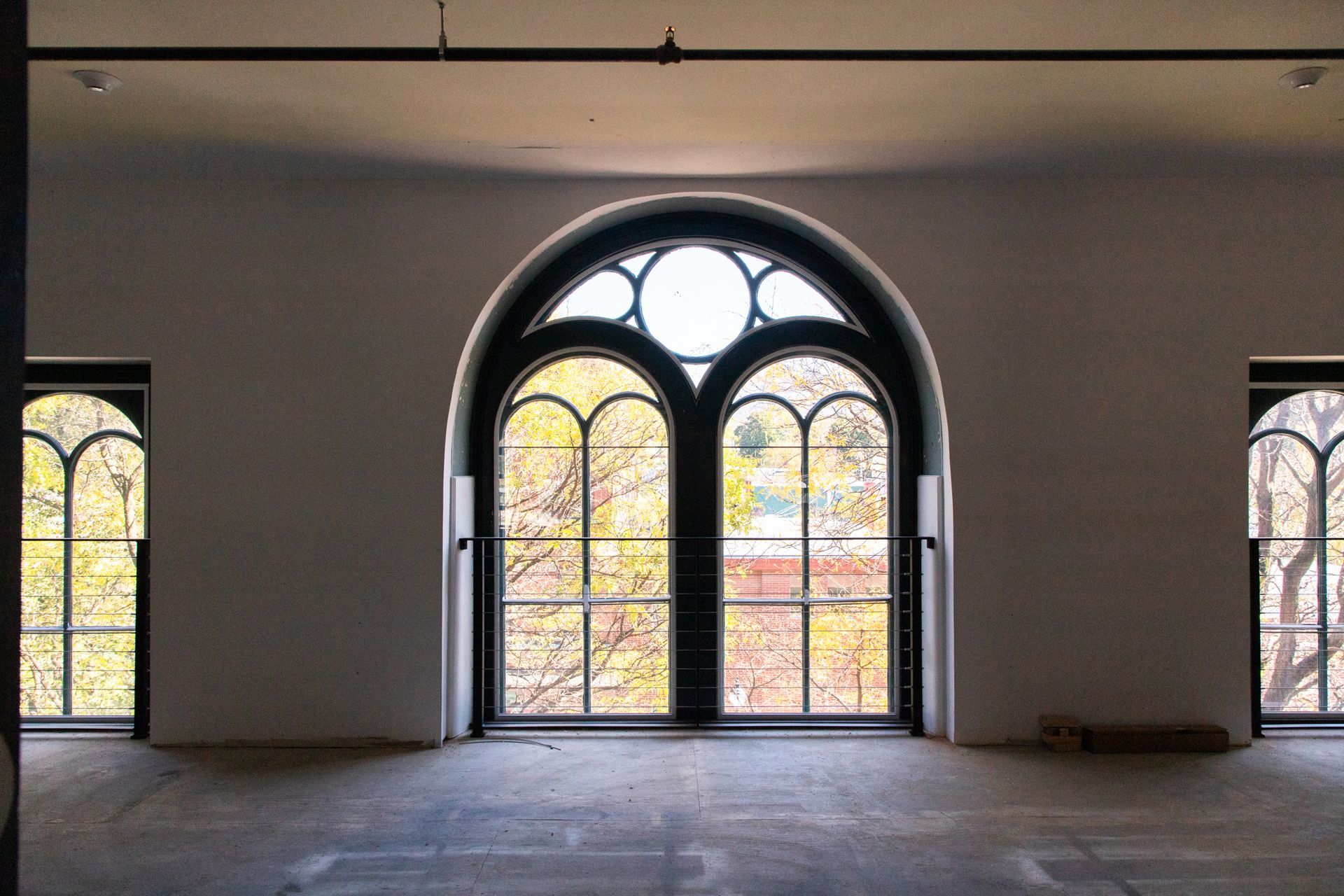 Empty room with large arched windows and double glass doors, lit by soft daylight