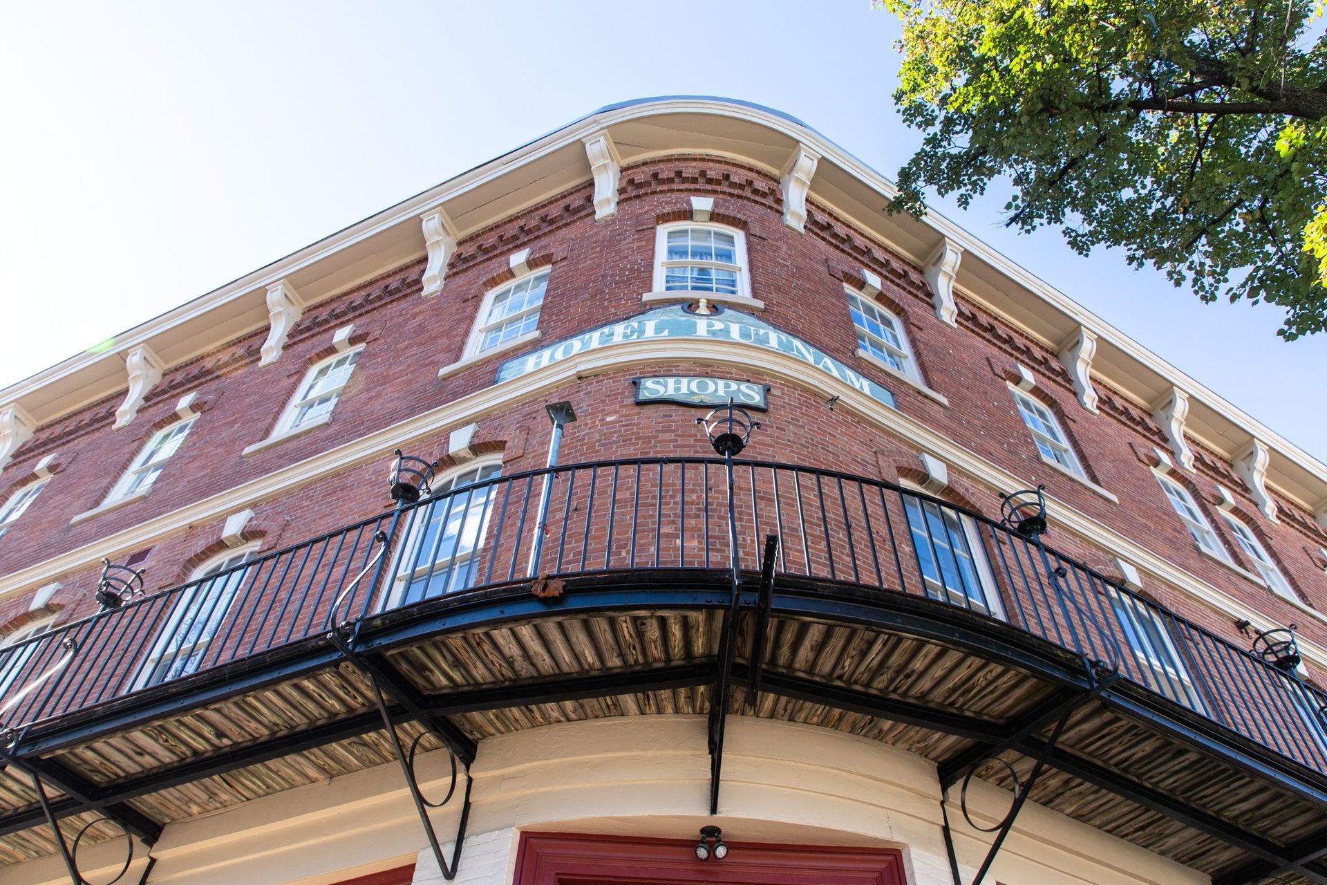 Low-angle view of a red-brick building with black balcony railing and blue sky above