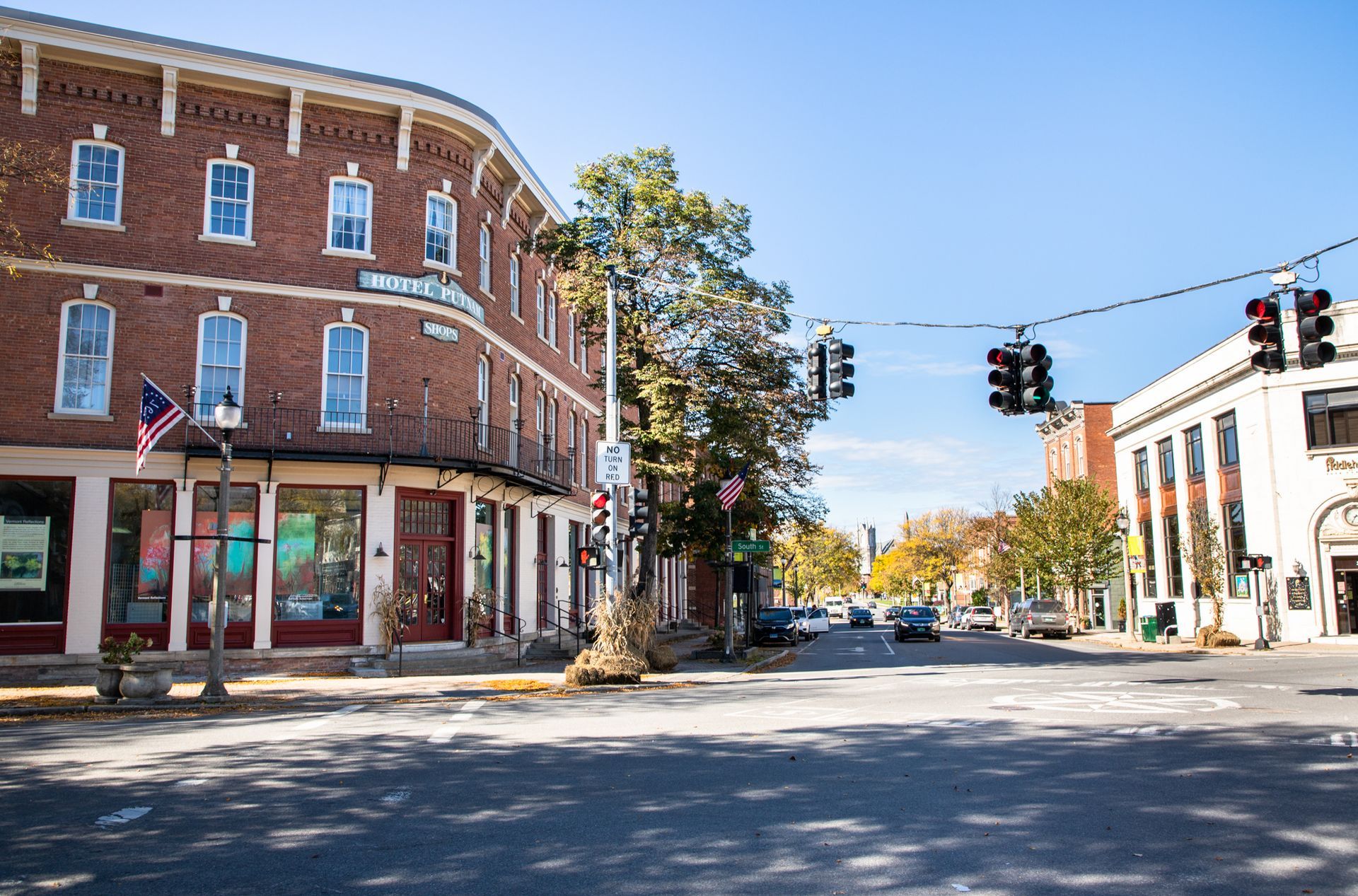 Sunny downtown street corner with red brick buildings, traffic lights, and a quiet intersection