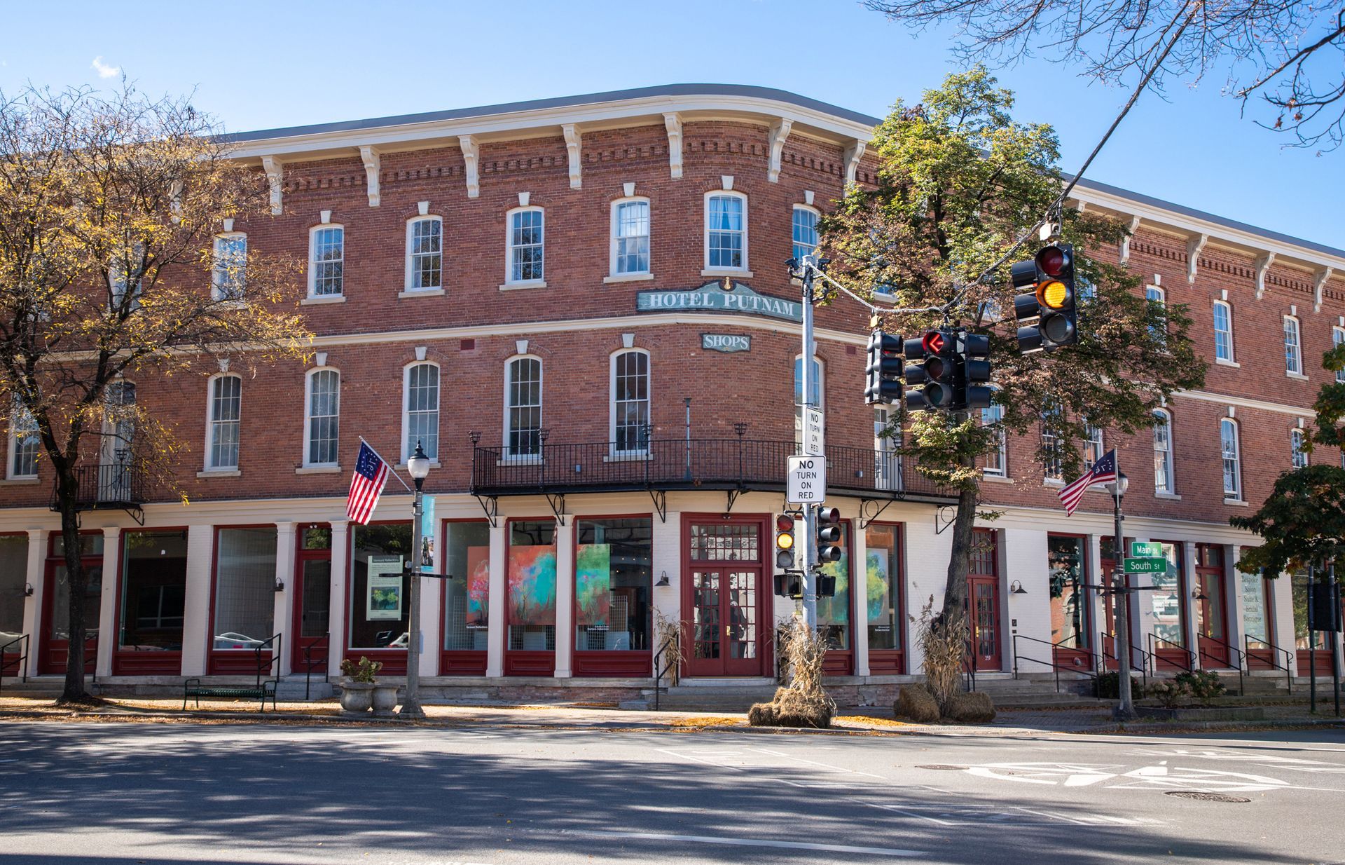 Brick corner building with storefronts and trees along a sunny street intersection