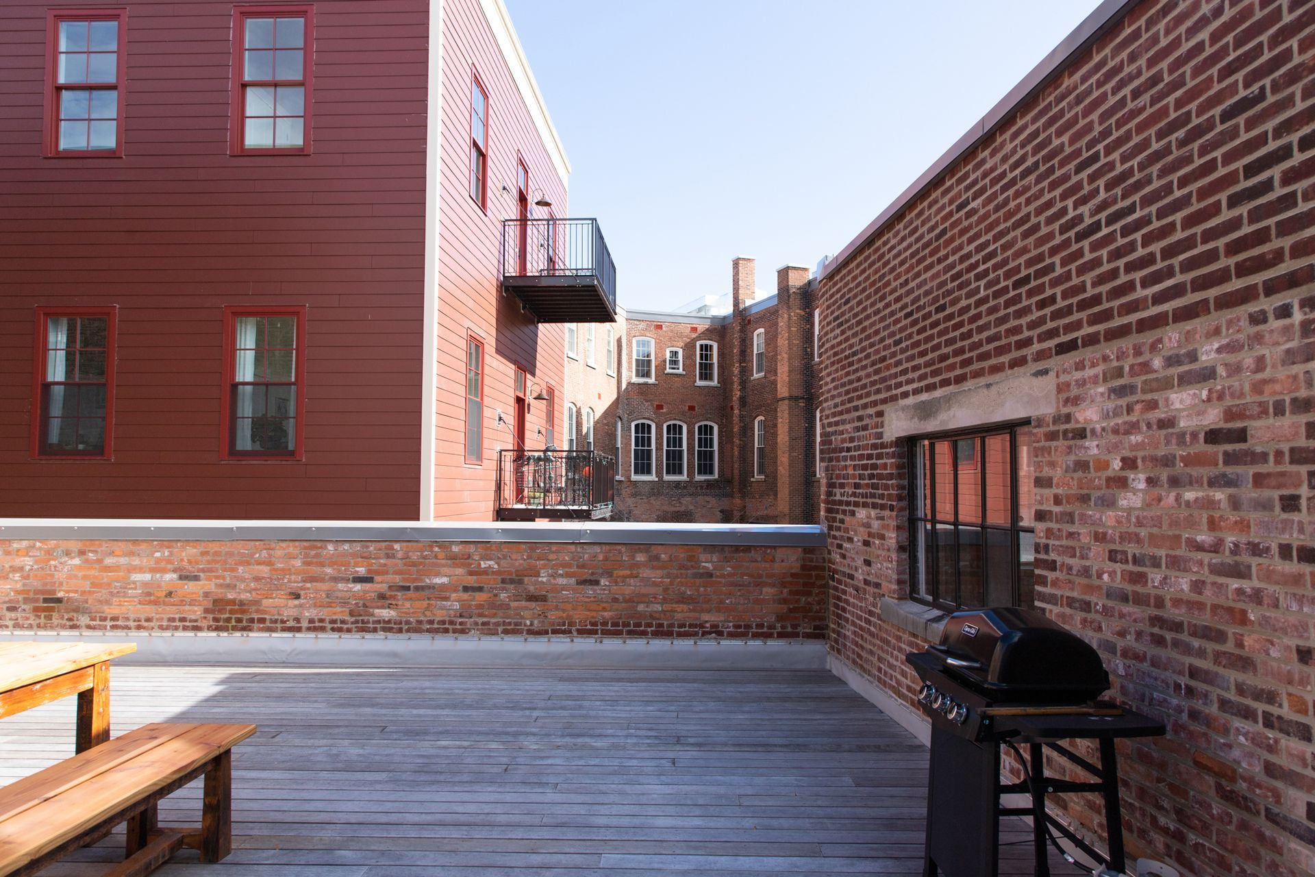 Rooftop deck with benches beside red brick buildings in sunlight