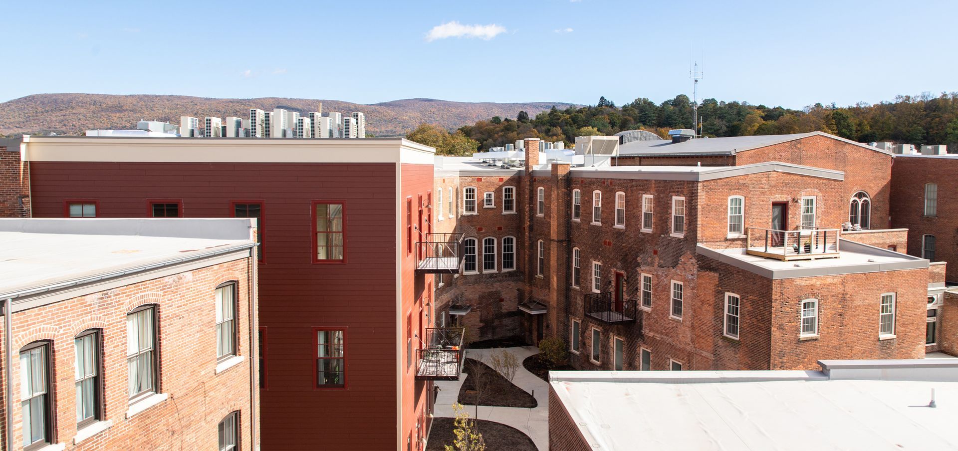 Brick apartment buildings and rooftops in a sunny urban neighborhood with distant hills