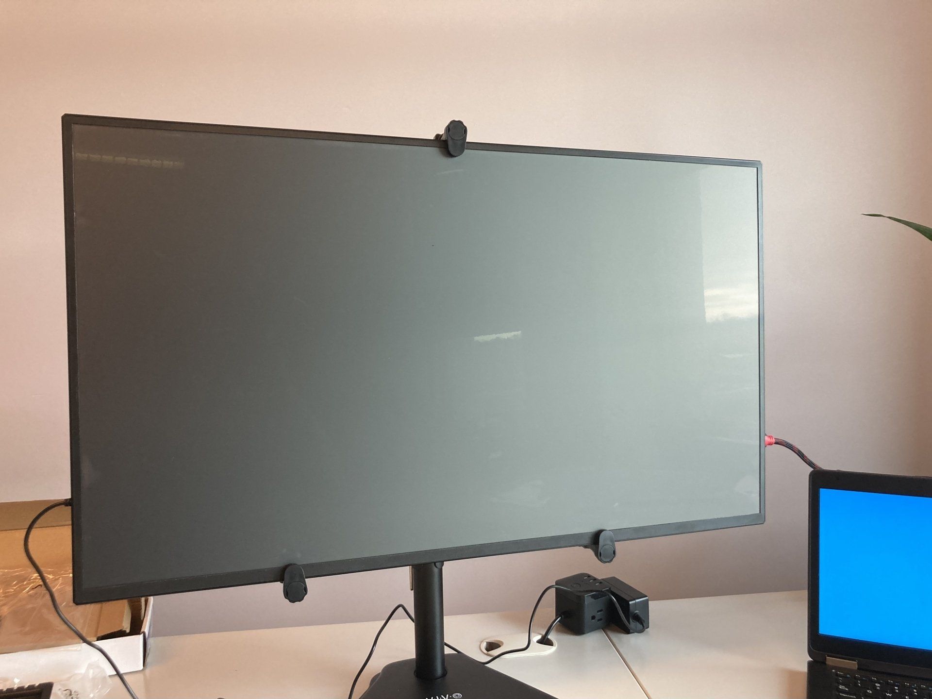 A computer monitor is sitting on a desk next to a laptop.