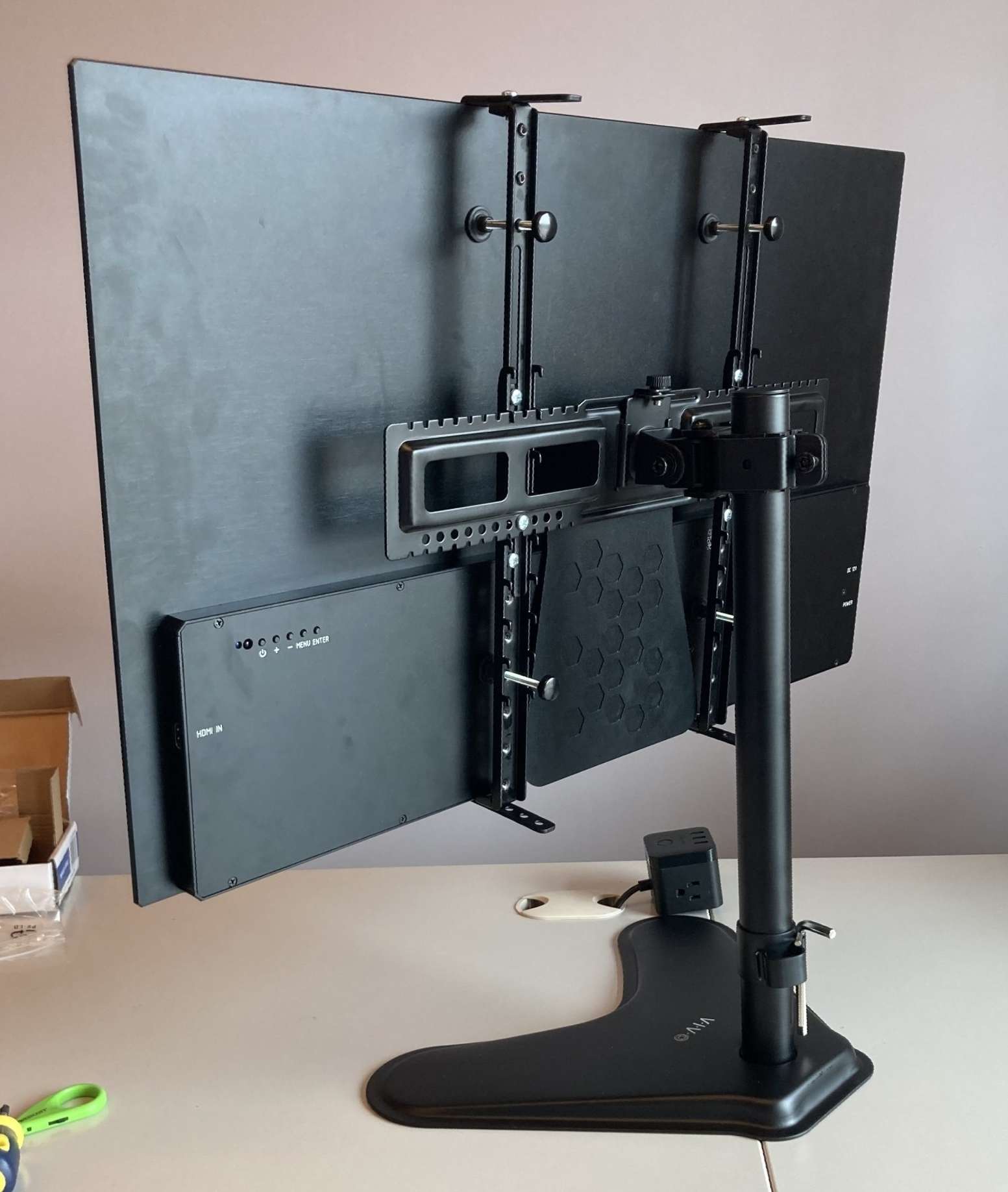 A computer monitor is mounted on a stand on a desk