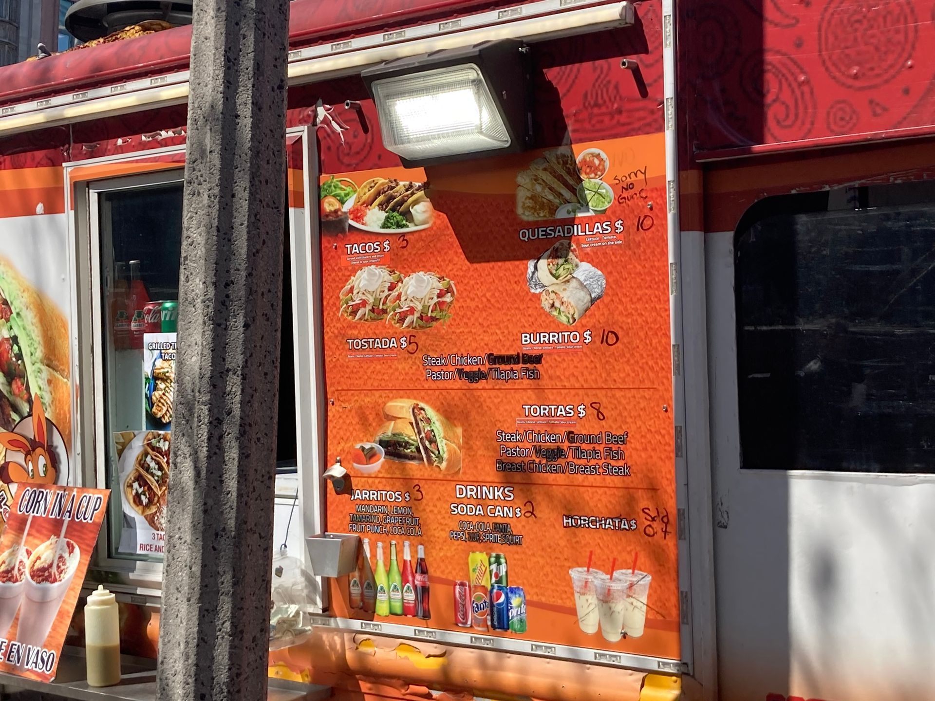 Printed food truck menu sign with crossed-out and written-over menu items.