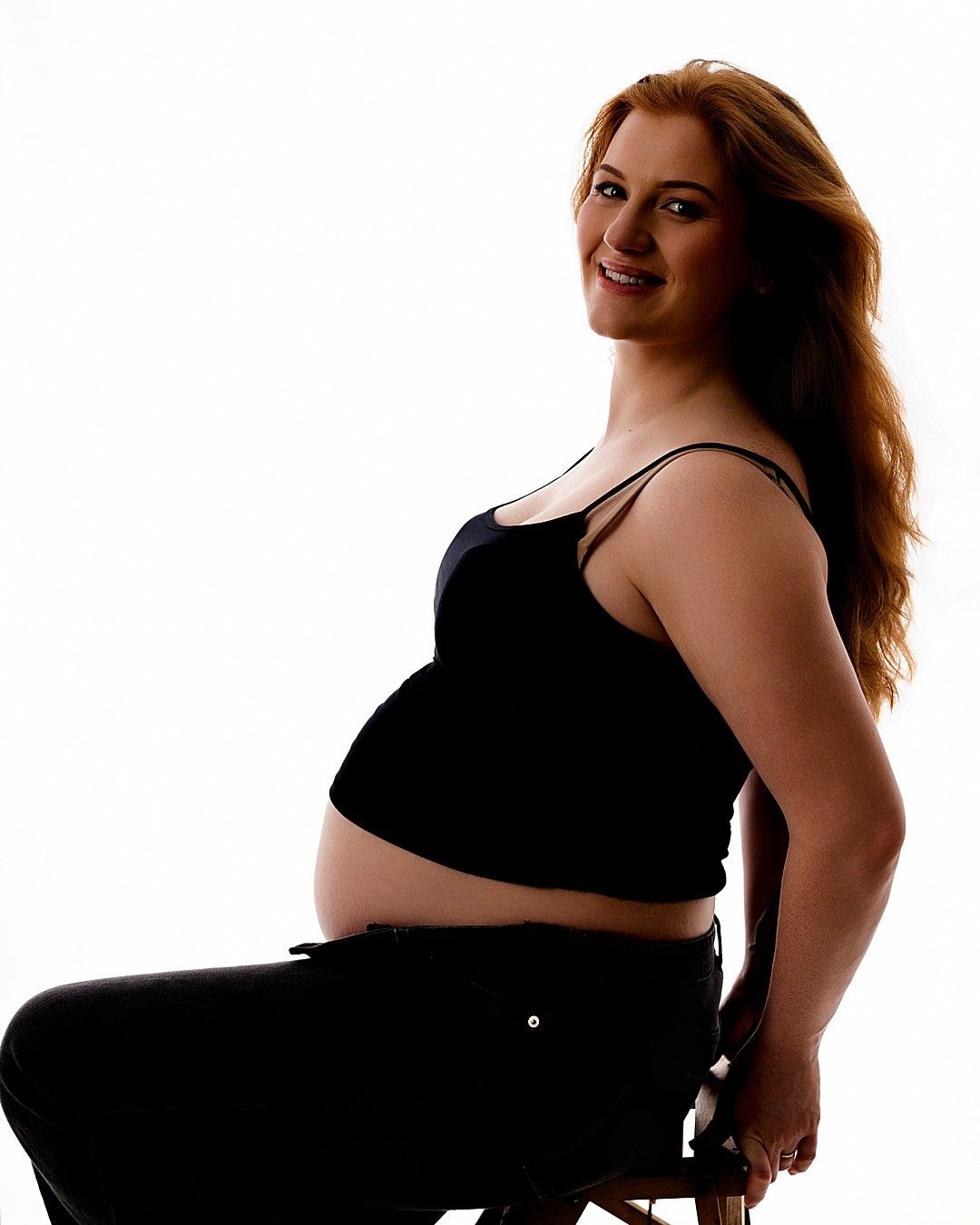 Elegant studio maternity portrait of a pregnant woman seated in profile during a maternity photography session in Dublin.