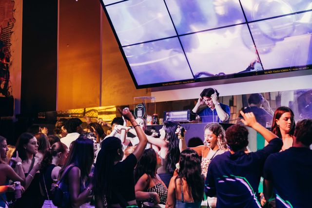 a group of people are dancing in a club while a dj plays music .