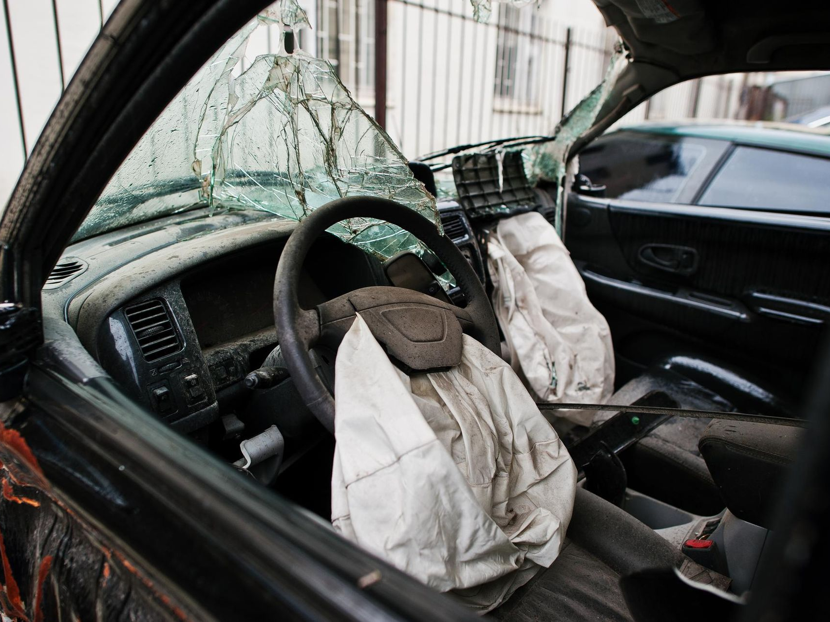 Damaged car interior with shattered windshield and deployed airbags after a crash