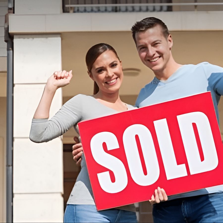 A Man And Woman Holding A Sold Sign In Front Of A House — SJP Law In Maroochydore, QLD