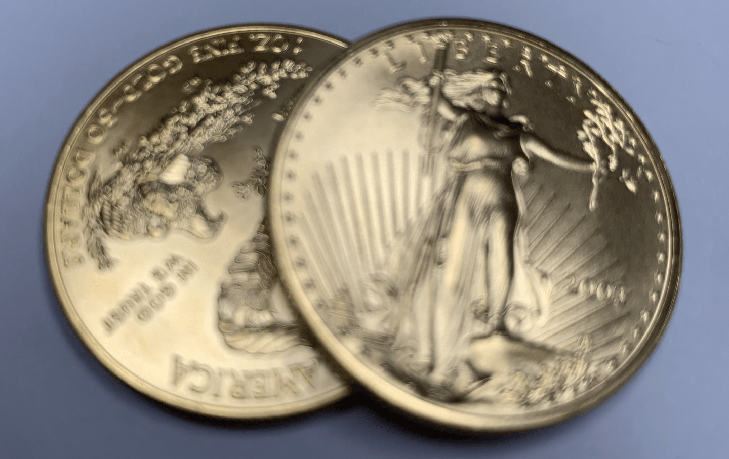 Two silver American Silver Eagle coins overlapping on a blue surface