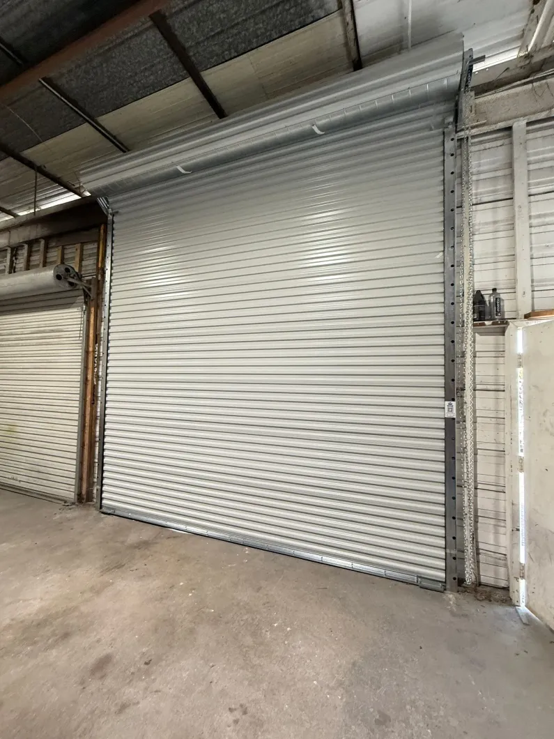 Closed white metal roll-up door in an industrial warehouse interior.