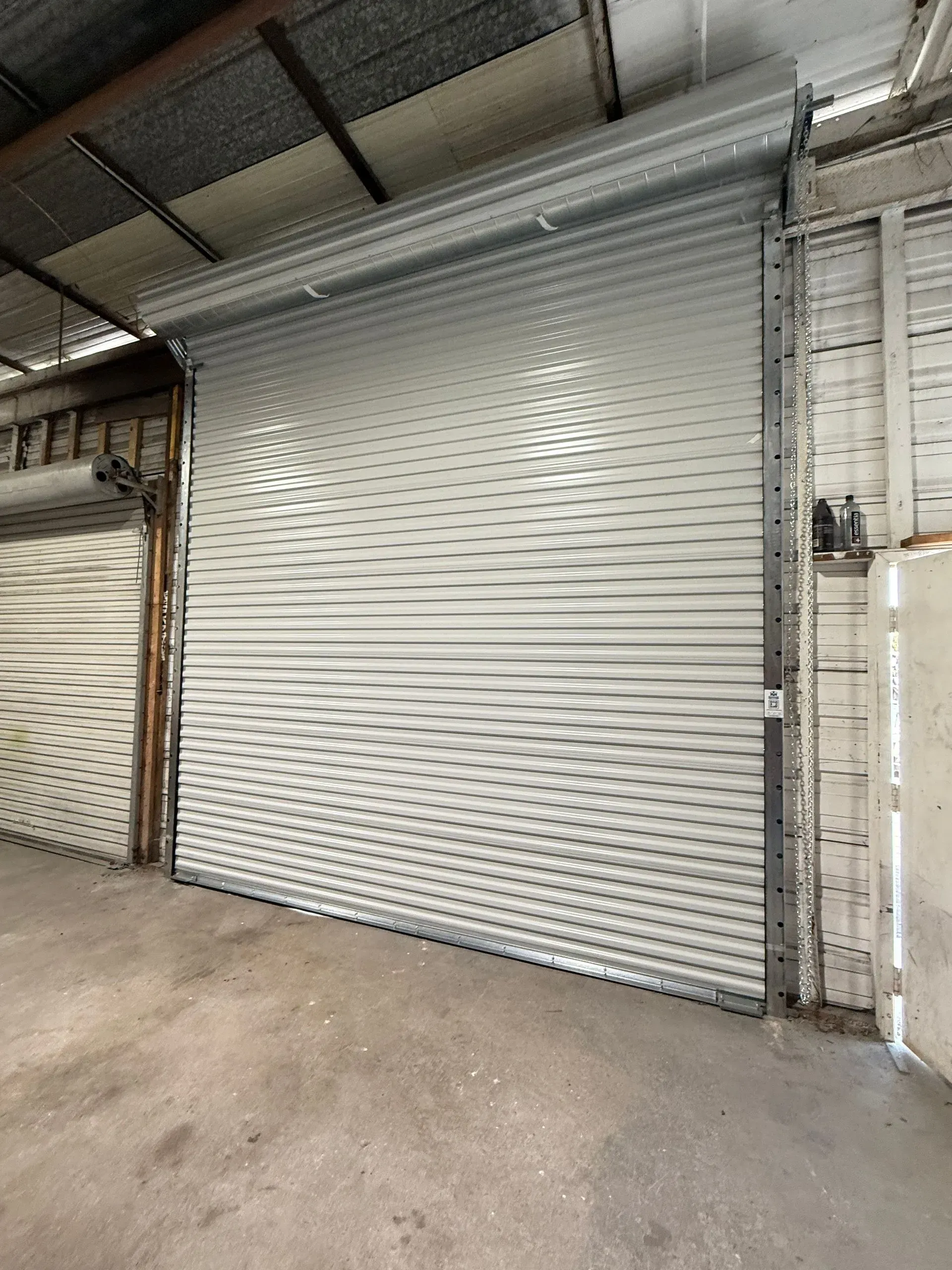 Closed white metal roll-up door in an industrial warehouse interior.