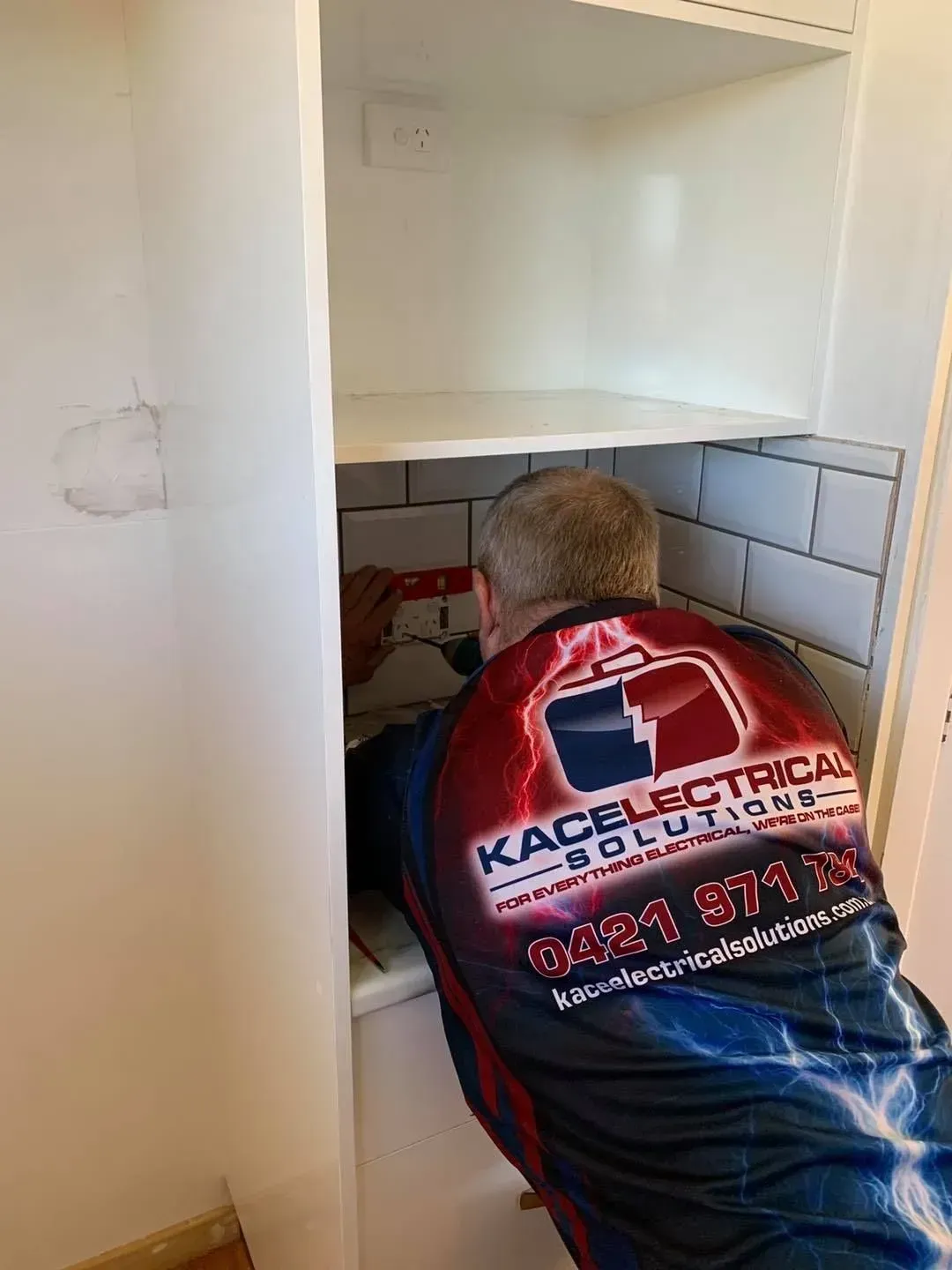 Electrician Working in a White Cabinet — KACE Electrical Solutions In Ramsay, QLD