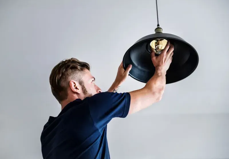 Man in a Blue Shirt Installing a Lightbulb — KACE Electrical Solutions In Highfields, QLD
