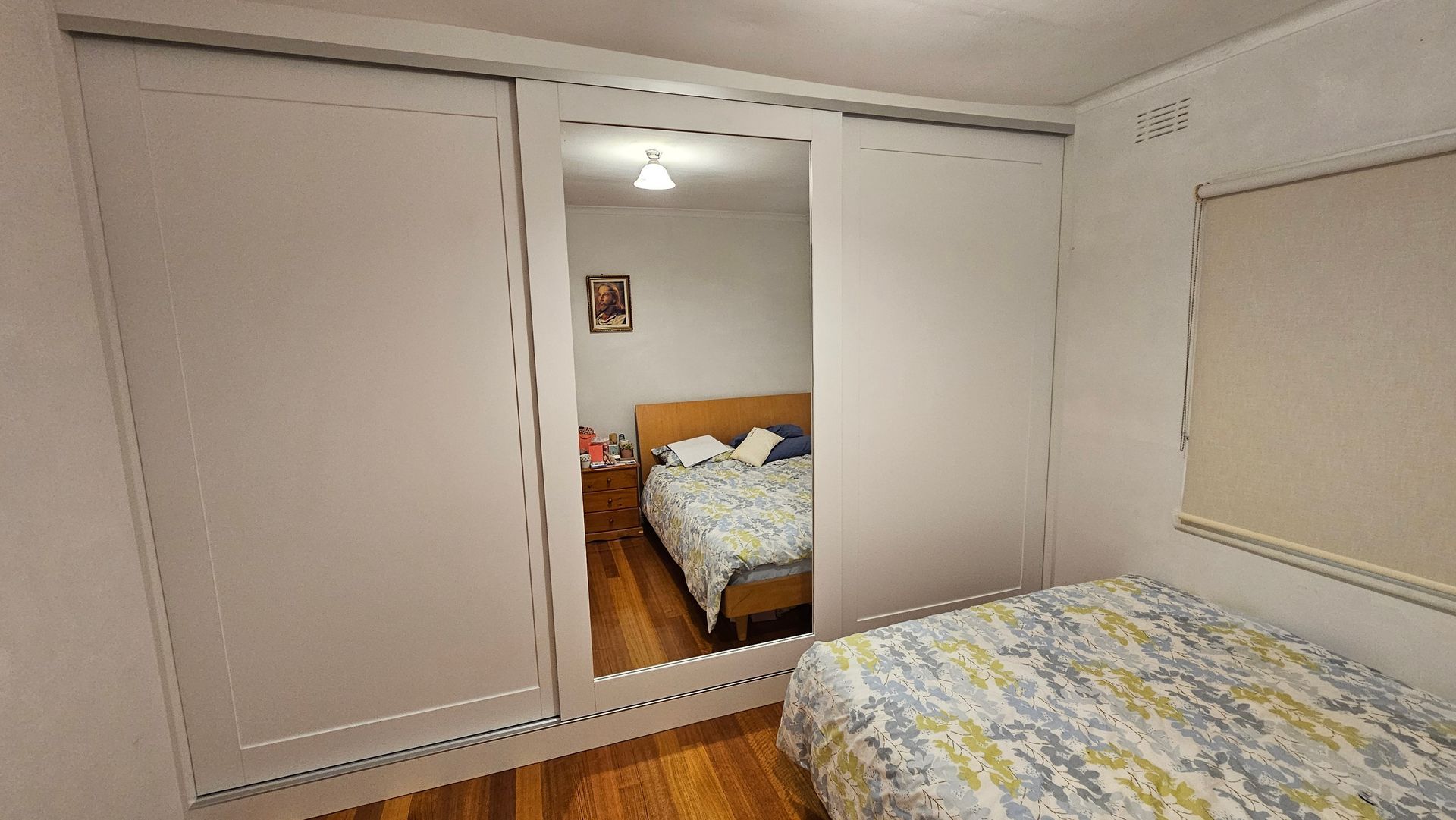 A bedroom with a bed and a large mirror on the wall.