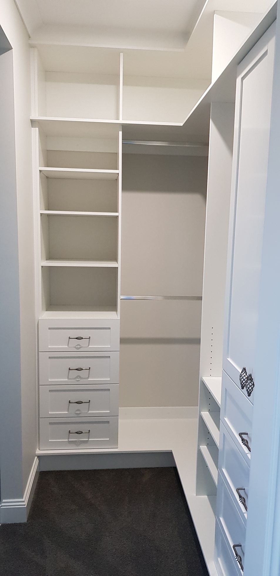 A walk in closet with lots of shelves and drawers.