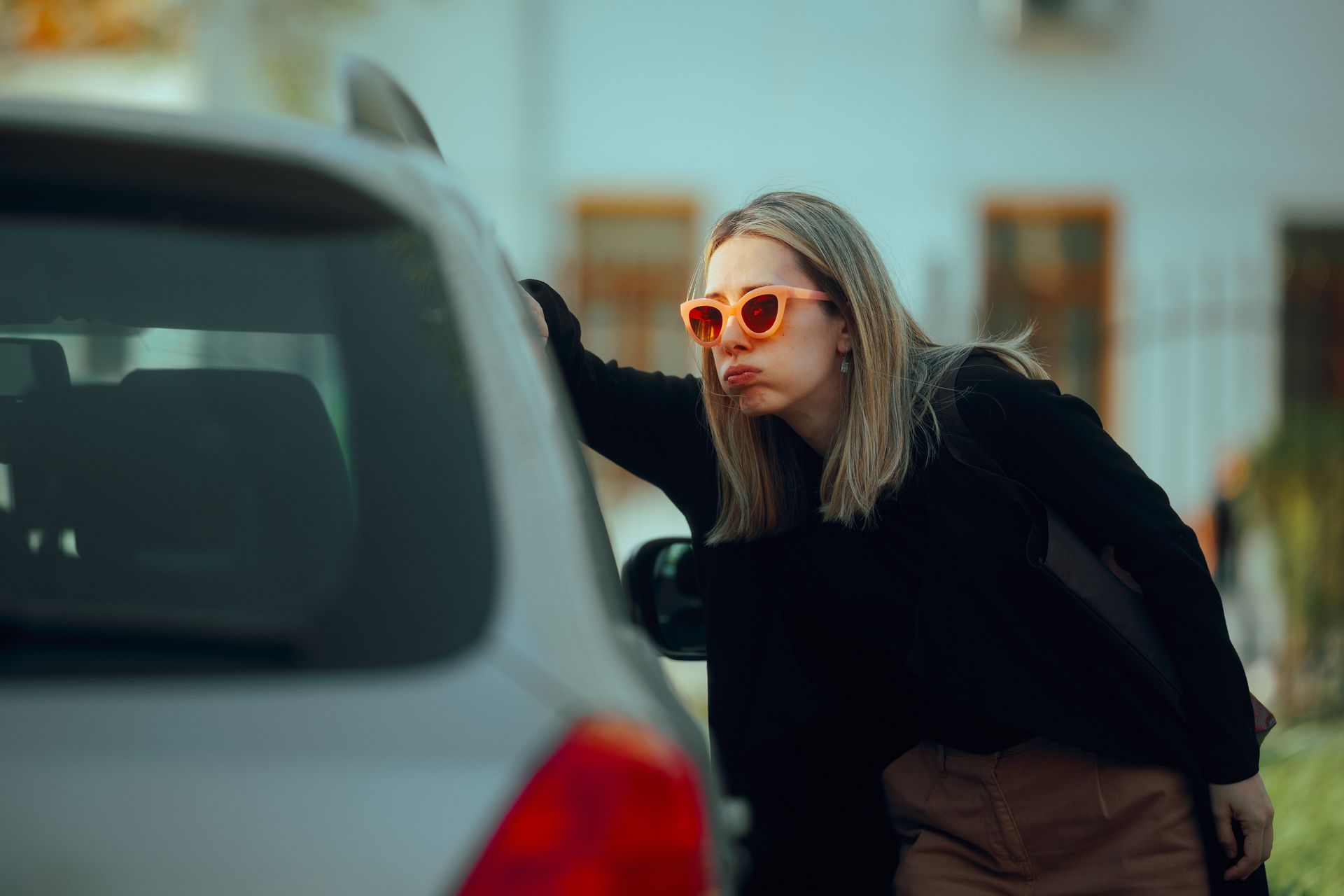 Woman locked out of her car looking inside confused. Woman locked out of her car looking inside confused.