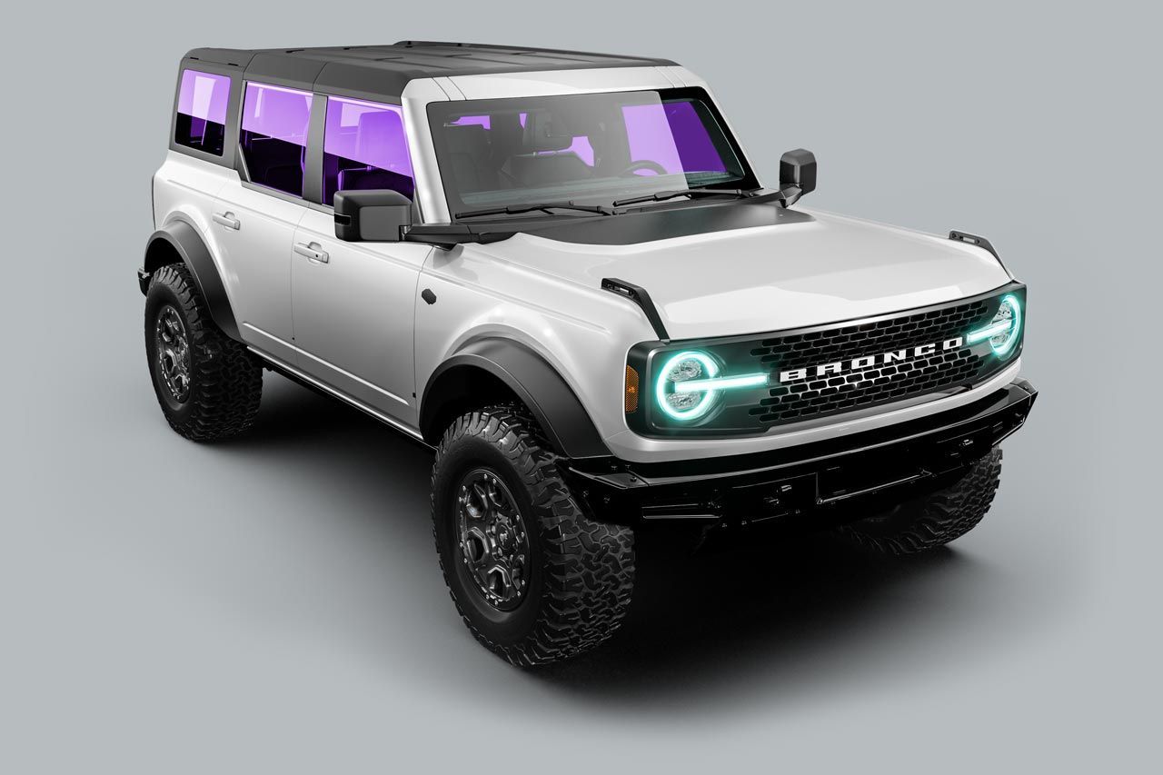 A white ford bronco with purple lights on the front is on a gray background.