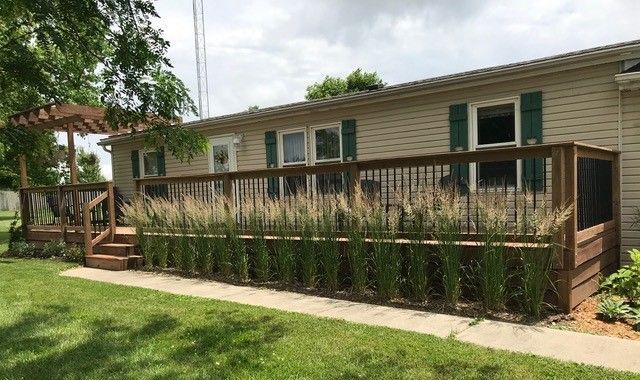 A man is standing on a wooden deck in front of a house.