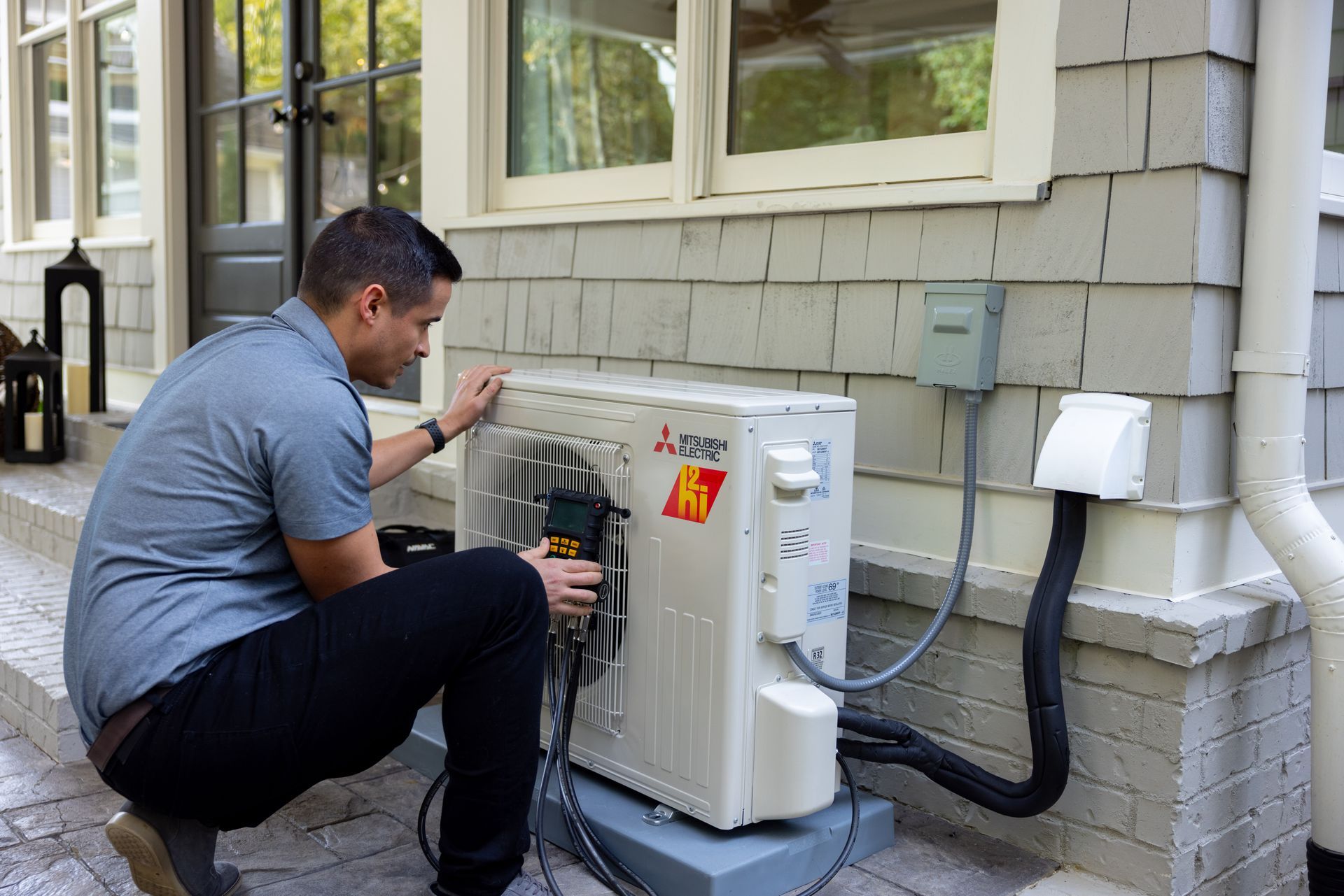 Pfluke Home Services technician installing a heat pump unit on a house exterior.